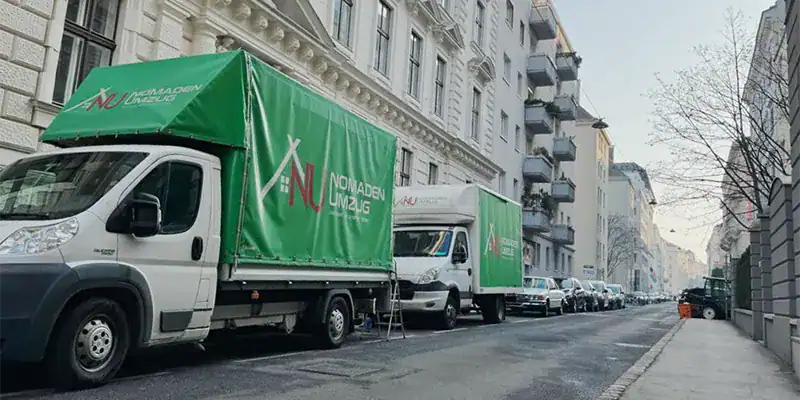 Nomaden Umzug Wien - Zwei Umzugs-LKWs mit Firmenbranding auf Wiener Wohnstraße