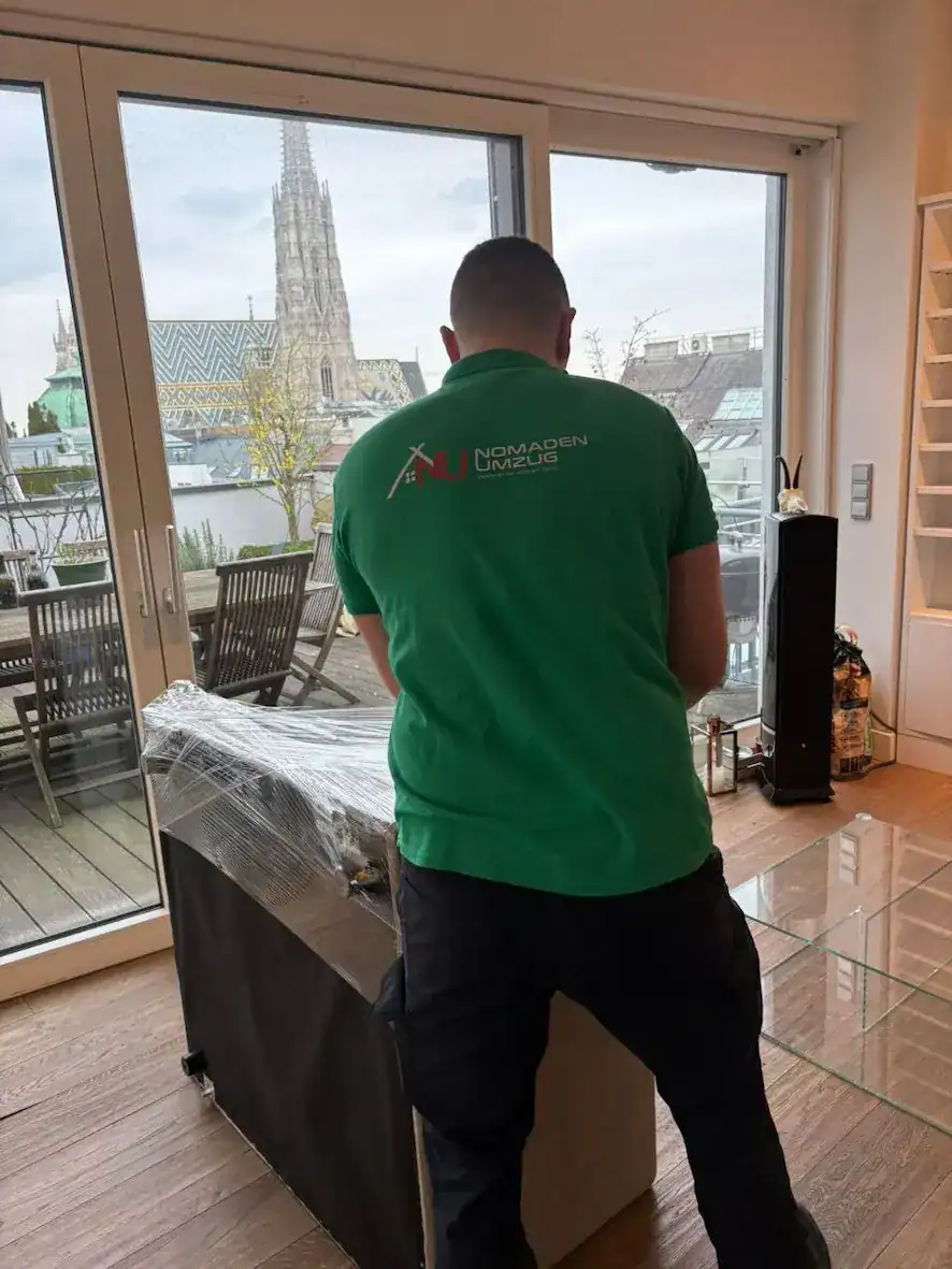 Nomaden Umzug Mitarbeiter verpackt Möbelstück mit Blick auf den Stephansdom in Wien
