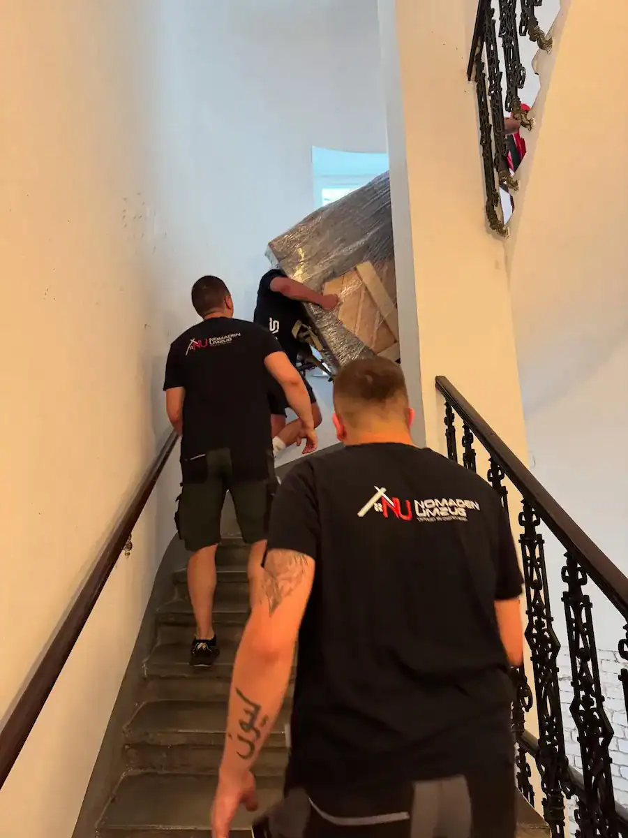 Nomaden Umzug Mitarbeiter tragen Möbel durch Wiener Altbau-Stiegenhaus