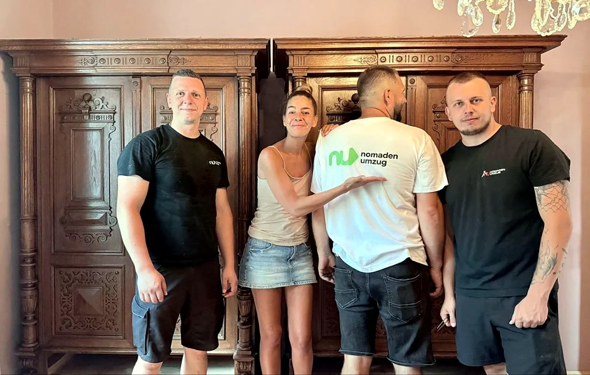 Nomaden Umzug Team mit Kundin vor zwei aufgebauten Altbau-Kästen aus Eichenholz
